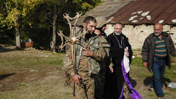 Военнослужащий и священнослужитель в Арцахе под обстрелом устанавливают крест